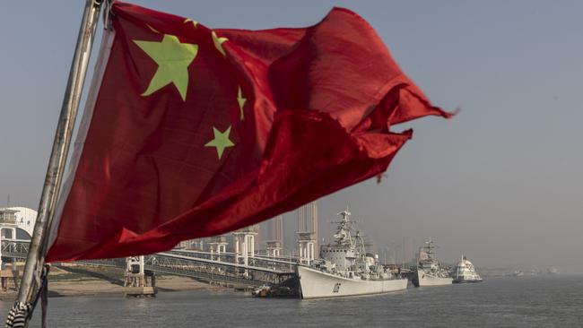 A Chinese national flag flies from a ferry as the retired People's Liberation Army (PLA) Navy Xian frigate ship, from left, and the Huaian frigate ship sit anchored on the Yangtze River in Wuhan. Picture: Qilai Shen/Bloomberg