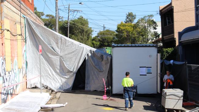 A silver cover ensures asbestos is contained as workers legally remove contaminated items from an inner Sydney address.