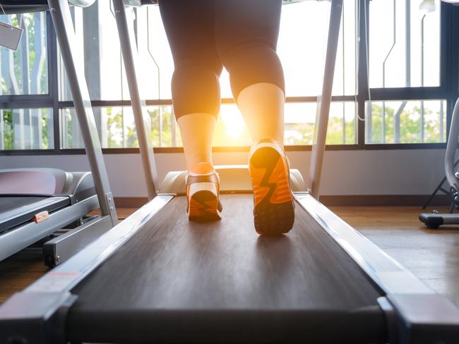 leg of fat woman being run or jog on belt of treadmill machine