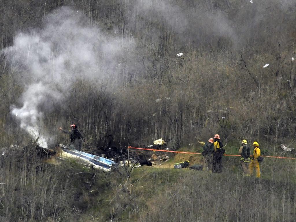 Firefighters attend the charred wreckage.