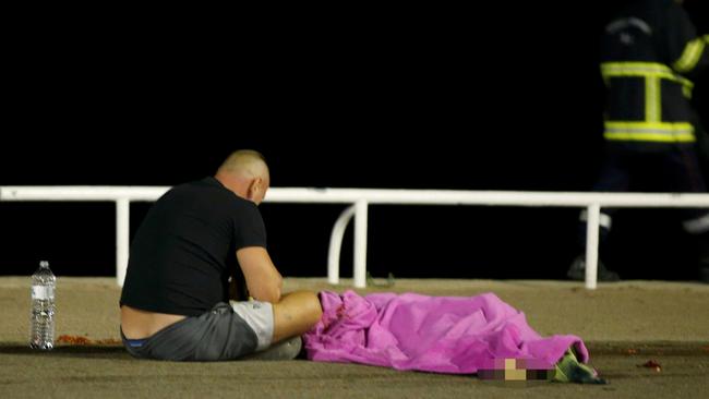 A man sits next to a body seen on the ground in Nice. Picture: <i>REUTERS/Eric Gaillard </i>