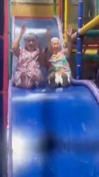 Grandmas show kids how it's done on ball pit slide