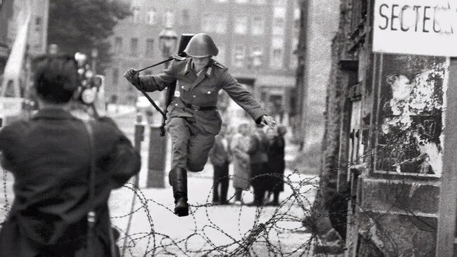 East German guard Conrad Schumann leaps across the nascent Berlin Wall to defect to West Germany in 1961.