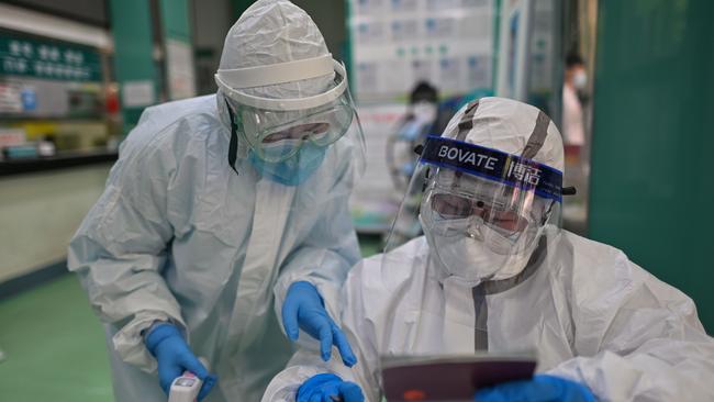 Medical workers check information as they take swab samples from people to be tested for the COVID-19 novel coronavirus in Wuhan.