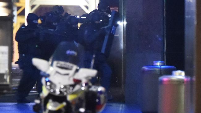 The officers storm the Lindt Cafe after shots are fired inside. Picture: Gordon McComiskie