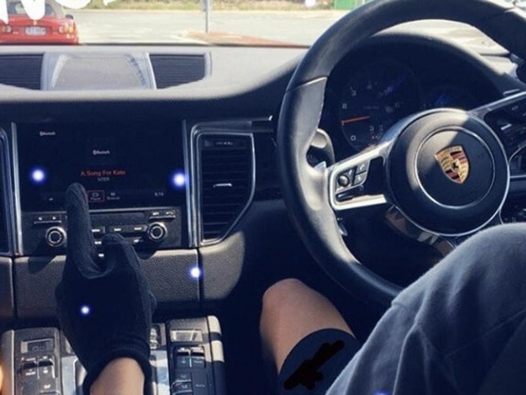 A Nothside Gang member at the wheel of a luxury Porsche.