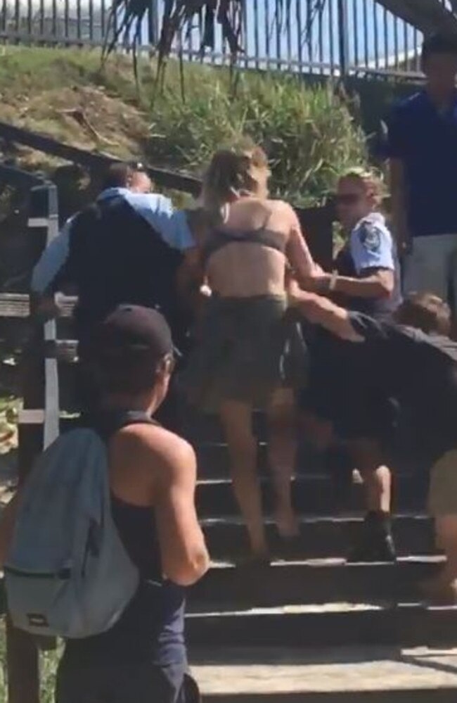 A woman is led away by police during an arrest at the beach.