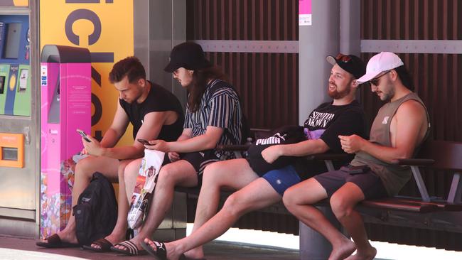 The Gold Coast has been singled out for its lax vax and sloppy mask wearing, with surging hospital numbers. Maskless men wait to catch the Light Rail at Surfers. Picture Glenn Hampson