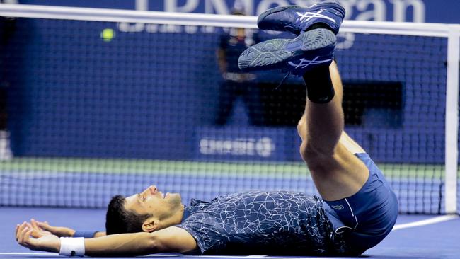 Novak Djokovic slumps to the court after his win over Juan Martin del Potro. Picture: AP