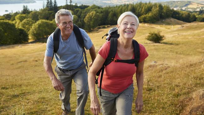 Portrait Of Senior Couple Climbing Hill On Hike Through Countryside In Lake District UK Together. Active retirees, retirement generic