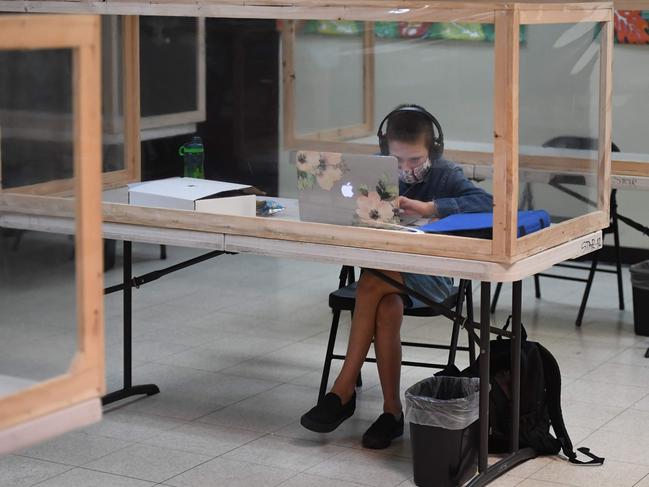 A student follows along remotely with their regular schoolteacher's online live lesson from a desk separated from others by plastic barriers in Culver City, California. Picture: AFP