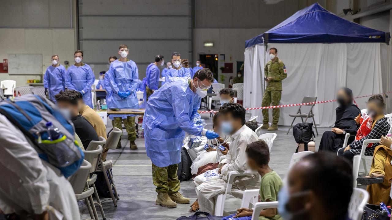 An Australian Defence Force member hands out juice to Afghanistan evacuees as they wait to be processed. Picture: Defence