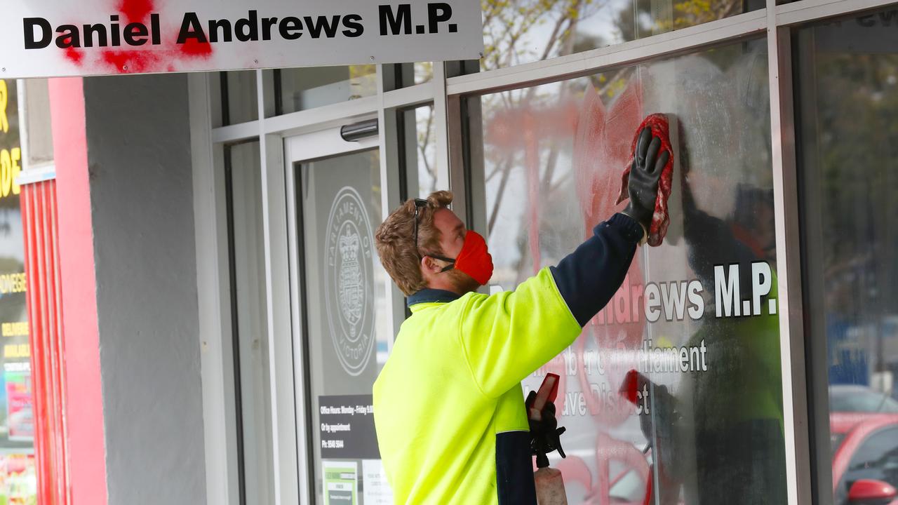 A cleaner removes paint from a window at Premier Daniel Andrews’ electorate office in Noble Park on Friday. Picture: David Crosling