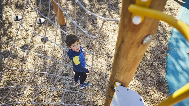 The Oakden playground has no stairs making it difficult for younger children to get to the top of the slide. Luca looking up to where he’d rather be. Picture: Matt Loxton