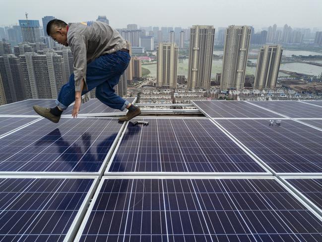 WUHAN, CHINA - MAY 15: A Chinese worker from Wuhan Guangsheng Photovoltaic Company works on a solar panel project on the roof of a 47 story building in a new development on May 15, 2017 in Wuhan, China. China consumes more electricity than any other nation, but it is also the world's biggest producer of solar energy. Capacity in China hit 77 gigawatts in 2016 which helped a 50% jump in solar power growth worldwide. China is now home to two-thirds of the world's solar production, though capacity and consumption remain low relative to its population.  Still, the country now buys half of the world's new solar panels  which convert sunlight into energy,  and are being installed on rooftops in cities and across sprawling fields in rural areas.  Greenpeace estimates that by 2030, renewable energy could replace fossil fuels as China's primary source of power, a significant change in a country considered the world's biggest polluter.  China's government has officially committed to development of renewable energies to ease the country's dependence on coal and other fossil fuels, though its strategic investments in the solar panel have created intense global competition. (Photo by Kevin Frayer/Getty Images)