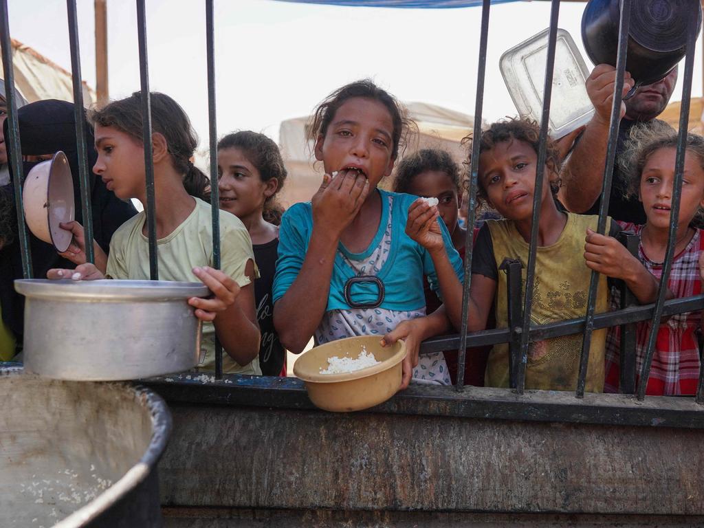 Palestinians receive cooked food rations as part of a volunteer initiative in a makeshift displacement camp in Mawasi Khan Yunis in the besieged Gaza Strip. Picture: Bashar Taleb / AFP