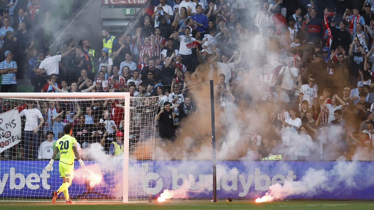 Victory’s Paul Izzo removes a flare from the pitch after a Melbourne City goal. Picture: Darrian Traynor/Getty Images