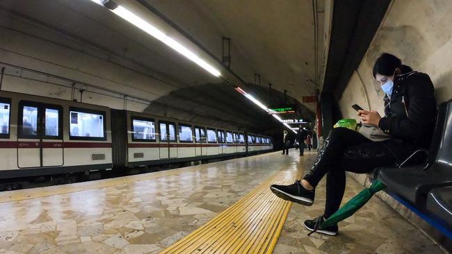 A woman wearing a protective face mask looks at her mobile phone at the Colosseo underground metro station in Rome. Picture: AFP