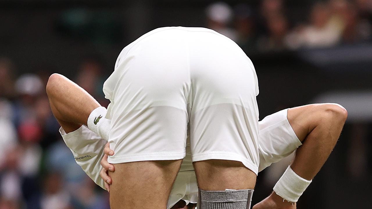 LONDON, ENGLAND – JULY 08: Novak Djokovic of Serbia bends over and looks through his legs as he stretches following a rally against Holger Rune of Denmark in his Gentlemen's Singles fourth round match during day eight of The Championships Wimbledon 2024 at All England Lawn Tennis and Croquet Club on July 08, 2024 in London, England. (Photo by Julian Finney/Getty Images)