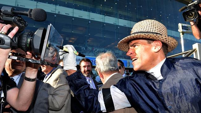 Fawkner jockey Nicholas Hall signs a camera after returning to scale. Picture: Jay Town