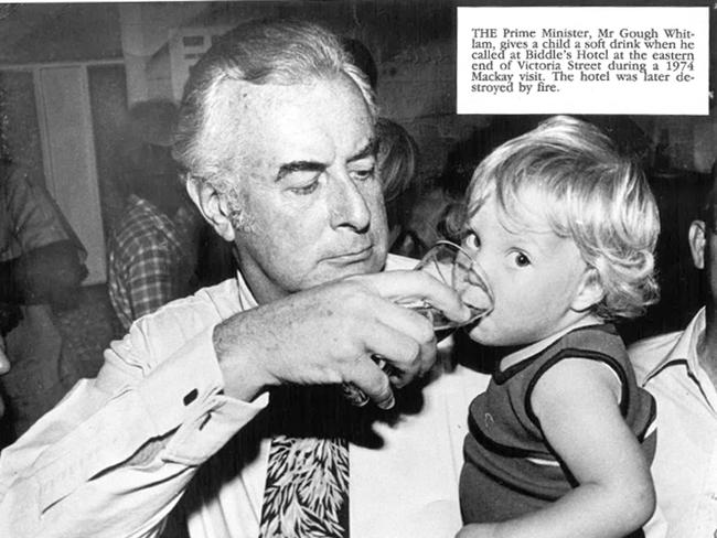 Historic: politics: Politicians The Prime Minister Gough Whitlam, gives a child a soft drink when he called at Biddle's Hotel at the eastern end of Victoria Street during a 1974 Mackay visit. The hotel was alter destroyed by fire. Photo Daily Mercury Archives