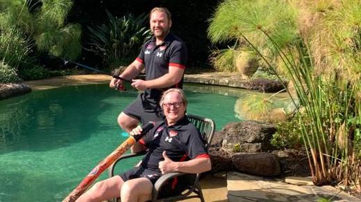 Kevin Sheedy and son Sam try to catch a Barra while playing the didgeridoo at their own 'Michael Long Billabong'.