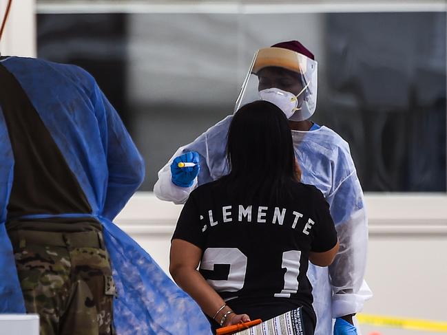 A medical personnel team member takes a sample from a woman at a walk-in and drive-through coronavirus testing site in Miami Beach, Florida. Picture: AFP