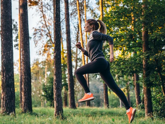 Young female athlete jogging in forest. Jogger doing morning physical training