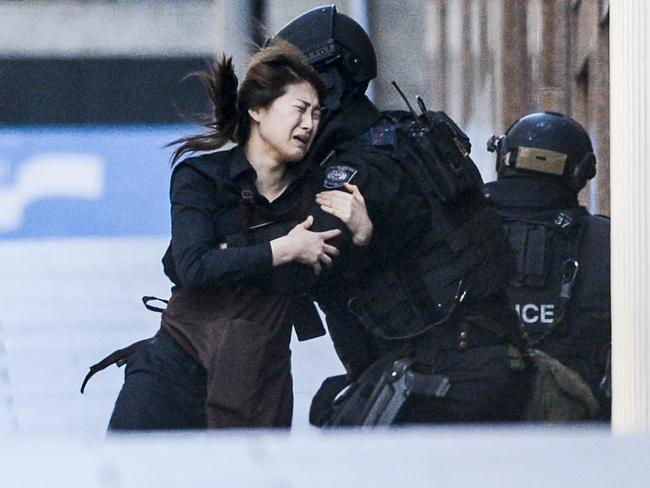 One of the hostages falls into the arms of a police officer after escaping the Lindt Cafe in Martin Place. Picture: Chris McKeen