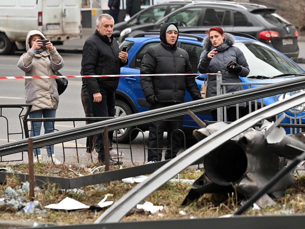 People react standing behind the cordoned off area around the remains of a shell in Kyiv. Picture: AFP