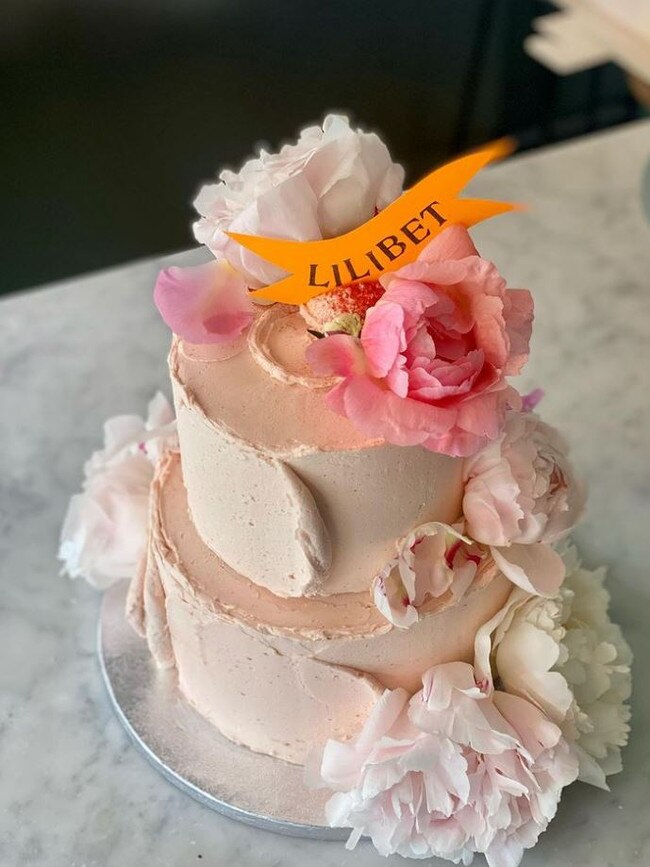 The light pink cake was adorned with flowers and had an orange ribbon on it that spelled out Lilibet. Picture: violetcakeslondon/Instagram.