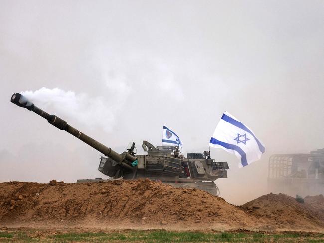 TOPSHOT - An Israeli army self-propelled artillery howitzer fires rounds from a position near the border with the Gaza Strip in southern Israel on December 10, 2023. Israeli forces pushed into southern Gaza on December 10, where hundreds of thousands of civilians have fled in search of shelter from bombardments and intense fighting with Hamas militants. (Photo by Menahem KAHANA / AFP)