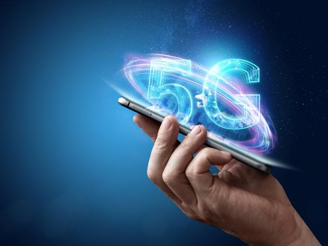 Creative background, male hand holding a phone with a 5G hologram on the background of the city. The concept of 5G network, high-speed mobile Internet, new generation networks. Copy space, Mixed media. Generic istock