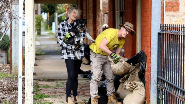 Mark Badcock and Tracey Wadsley, with their dog Ziggy, sandbag their property on the main street of Echunga. Picture: Kelly Barnes