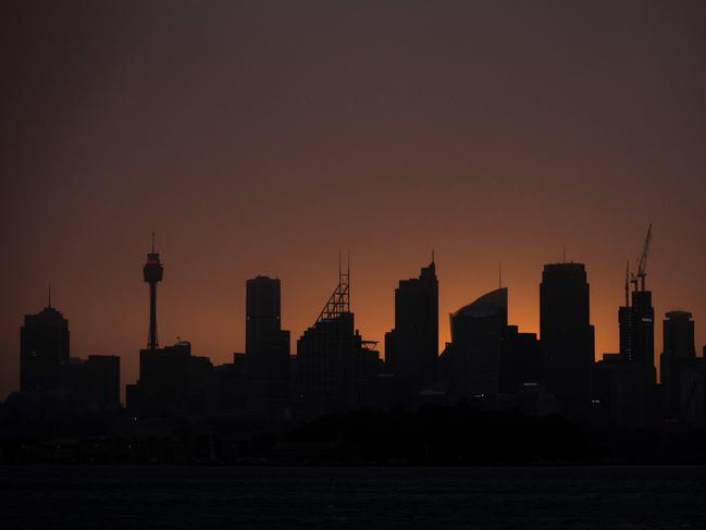 The sun sets behind the city skyline as smoke haze from bushfires drifts over the CDB in Sydney, Tuesday, November 12, 2019. At least 13 ferocious bushfires are burning at emergency level across the eastern Australian state of New South Wales (NSW), with one blaze just 20 kilometres outside Sydney. (AAP Image/Paul Braven) NO ARCHIVING