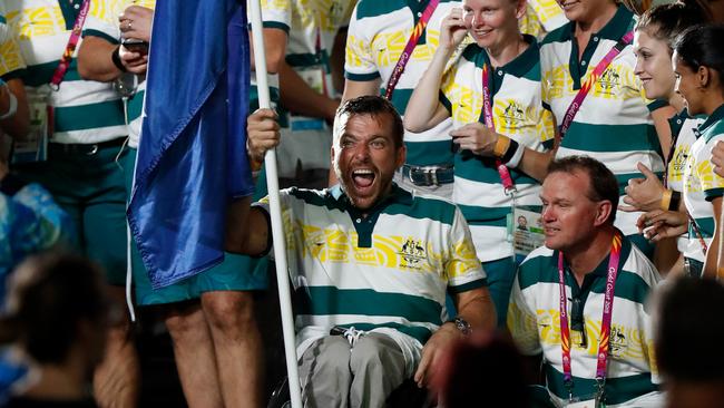 Kurt Fearnley carries the Australian flag.