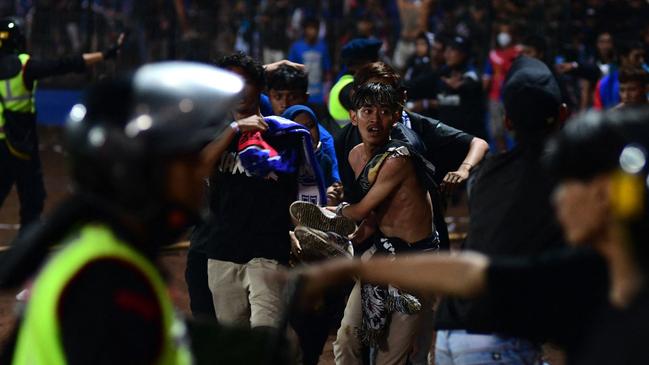 Supporters carry a man injured in a stampede at Kanjuruhan stadium on Sunday. Picture: AFP