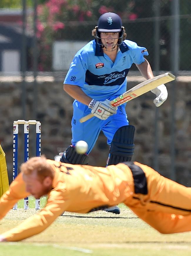 Sturt’s Tom Kelly gets a shot away as Glenelg bowler Craig Dand lunges...