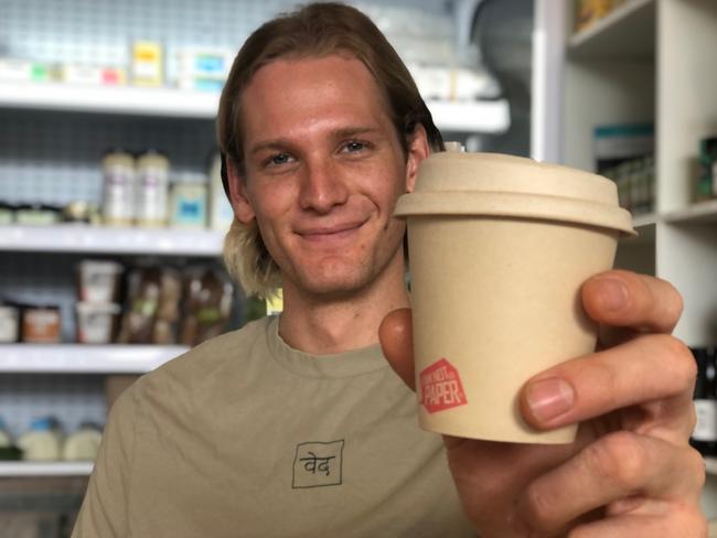 Chris Hayward has opened Veda, an organic fair-trade coffee shop, cafe and grocer on Lawrence St, Freshwater. He is holding a recyclable coffee cup made with sugar cane plant pulp. Picture Julie Cross