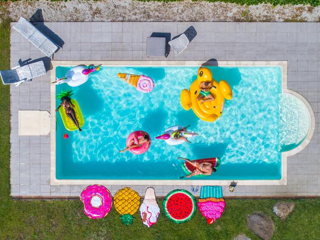 Group of friends having party in a swimming pool and tanning on airbeds, drone view. Picture: Supplied