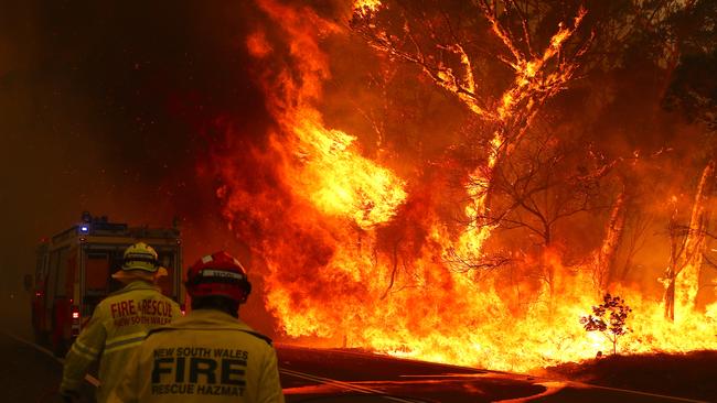 Fire and Rescue personal run to their truck as a bushfire burns next to a major road and homes at Bilpin on December 19, 2019. Picture: Getty