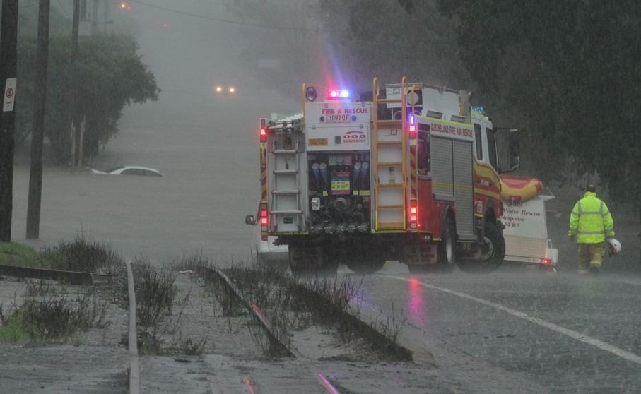 Emergency service crews check out a submerged vehicle in floodwaters at the Granville end of Kent St. Picture: Robyne Cuerel