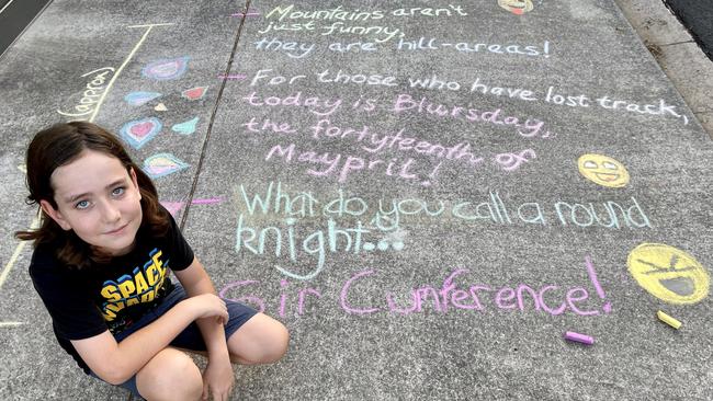 Darcy, 12, shows off the jokes her family has written on a footpath outside their Arana Hills home.