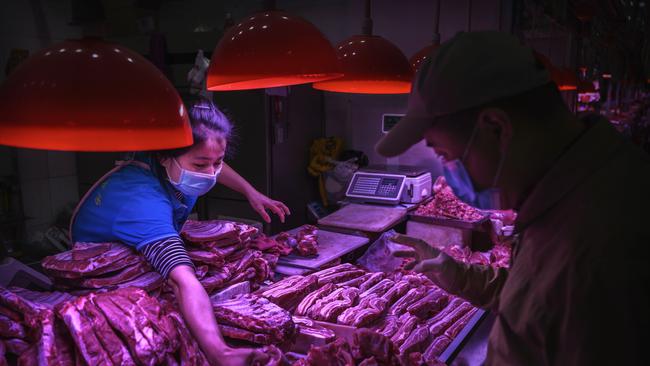 A Chinese meat vendor wears a protective mask as she serves a customer at her stall at a food market on April 24 in Beijing, China. Picture: Getty