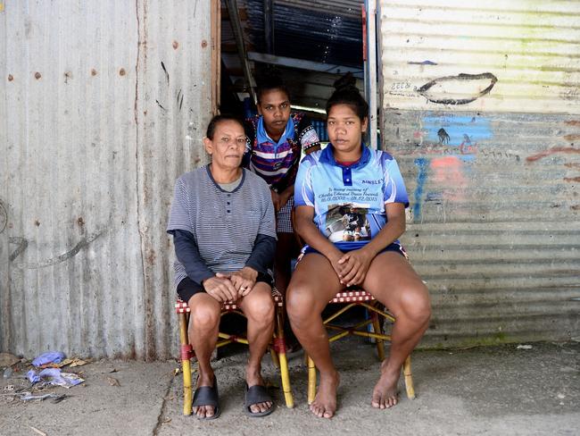 Dellaroy Fourmile sits outside her old home with her daughters Melita and Ainsley. Ms Fourmile, along with her husband, raised her 12 children in this house, which had no bedrooms at the time. Picture: Isaac McCarthy