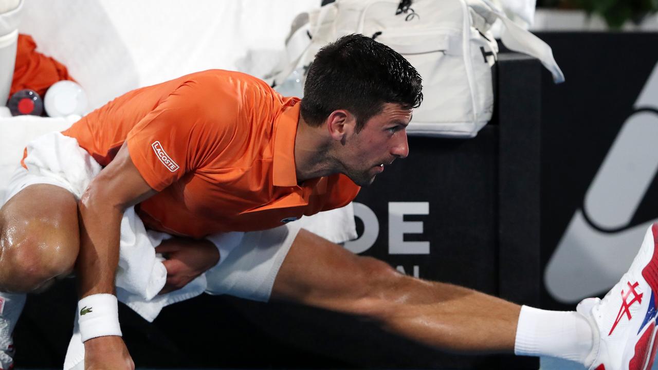 Novak Djokovic stretches his injured leg. (Photo by Sarah Reed/Getty Images)