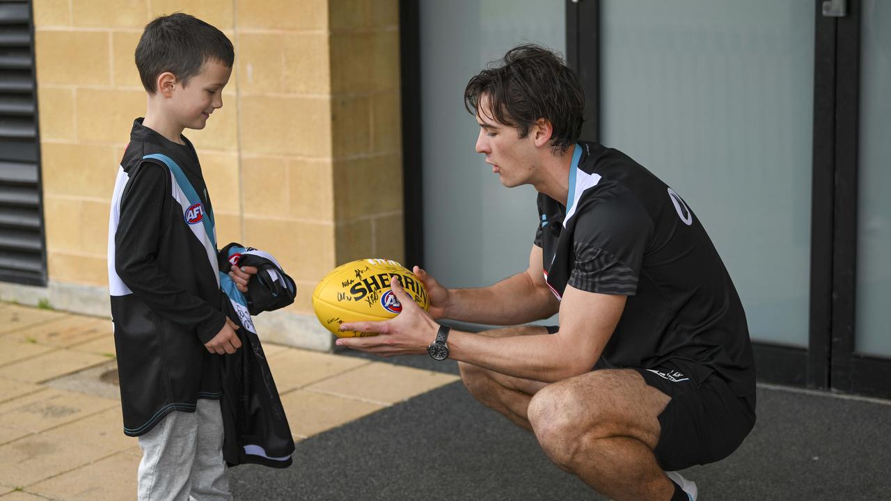 Xavier receiving a team signed football and guernsey from Connor Rozee. Picture Mark Brake