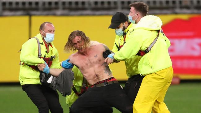 A pitch invader is taken from the field by masked security at Optus Stadium on Thursday night. Picture: Getty Images