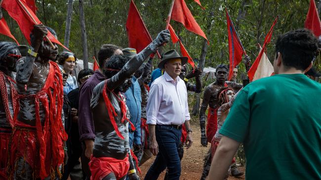 Prime Minister Anthony Albanese is escorted through the Garma camp site by the Red Flag Dancers during Garma Festival.