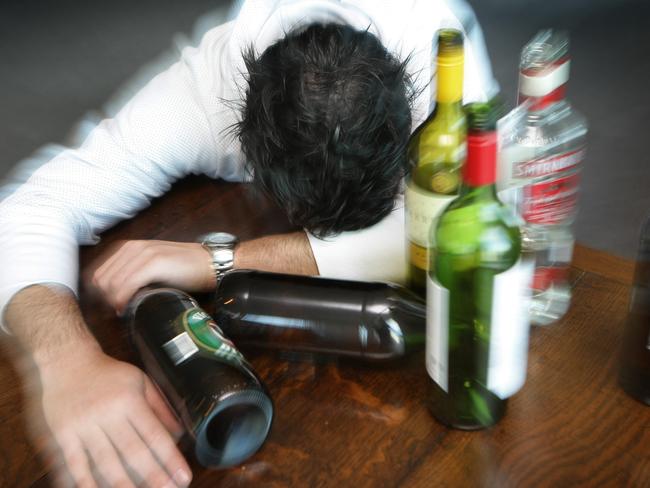 Generic photo of a man surrounded by alcohol bottles. Binge drinking. Drunk.